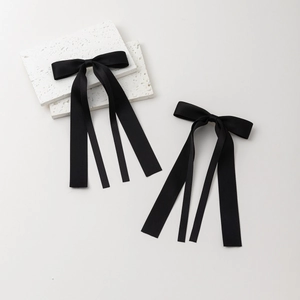 Détail de nœuds en satin noir avec de longs rubans style ballet sur un support en pierre