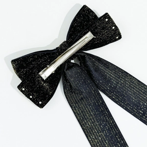 Detail of elegant black velvet bow hair clip with gold shimmer threads and metal alligator clip