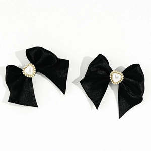Detail of black satin bow hair clips with heart faux pearls and gold beaded edges