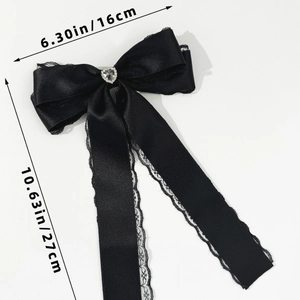 Detail of black satin bow hair clip with crystal heart and delicate lace trim edges