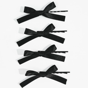 Lot de quatre barrettes à nœuds en satin noir avec épingles en métal sur fond blanc
