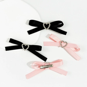 Détail de barrettes à cheveux avec nœud en satin, boucles cœur strass et pinces crocodile