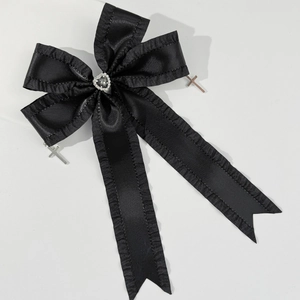 Macro detail of black ribbon hair clip featuring a heart gemstone and silver cross charms