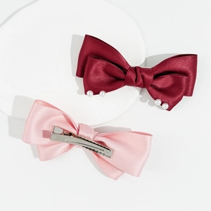 Détail de barrettes à nœuds en satin avec perles blanches et pince croco en métal
