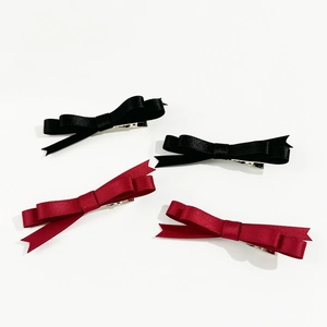 Lot de quatre barrettes à nœuds en satin noir et bordeaux sur fond blanc épuré
