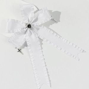 Detail of white ruffled bow hair clip with black heart stone and silver crosses