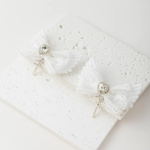 Détail de nœuds à cheveux en dentelle blanche avec ailes pailletées et croix argentées