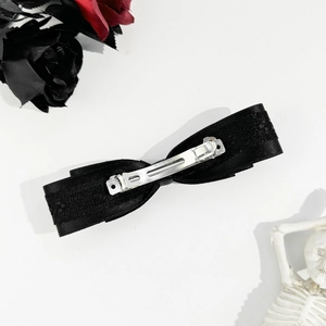 Detailed view of black lace ribbon bow hair clip with silver metal spring fastener