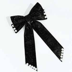 Detail of black velvet bow hair clip with gold glitter and white faux pearls decor