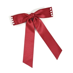 Détail du nœud papillon en satin rouge élégant orné de petites perles blanches