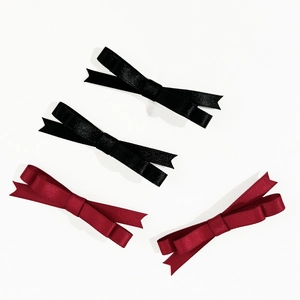 Lot de quatre barrettes nœuds en satin noir et rouge vin sur un fond blanc pur