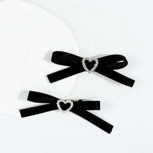 Détail de barrettes en satin noir avec centre en strass en forme de cœur sur fond blanc