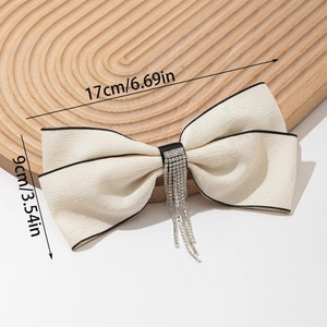 Détail du nœud papillon de 17x9cm orné de strass brillants et de longs pompons