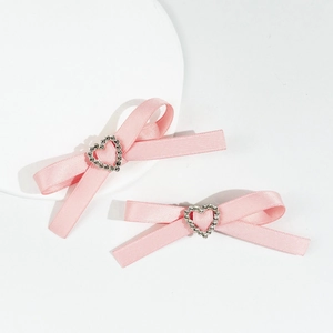 Détail de pinces à cheveux en satin rose ornées d'un cœur en strass sur le dessus