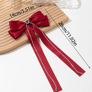 Detail of red satin bow hair clip with heart rhinestone and long crystal fringe tassels