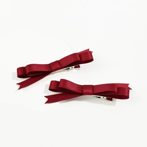 Détail de deux nœuds pour cheveux en satin bordeaux avec pinces crocodiles en métal