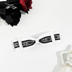 Macro view of white satin bow hair clip with black lace trim in Gothic style
