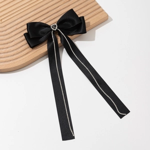 Detail of black satin bow hair clip with heart rhinestone and sparkling tassel fringe