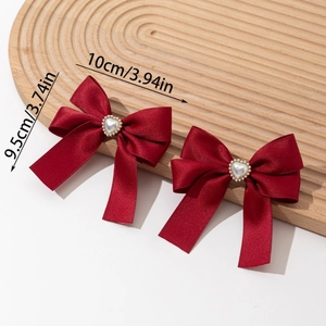 Detail of red satin bow hair clips with pearl heart centers on a wooden display board