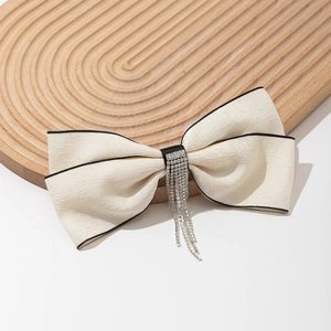 Barrette nœud élégante avec strass et glands sur une planche en bois décorative