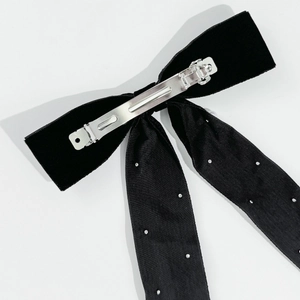 Detailed back view of a black velvet bow hairclip with silver studs and metal spring clip