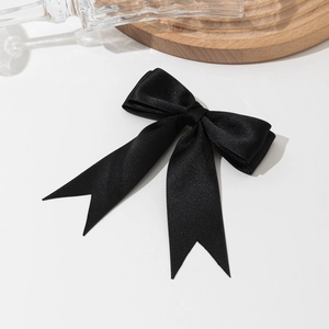 Elegant black satin bow hair clip with long ribbon tails on white minimalist background