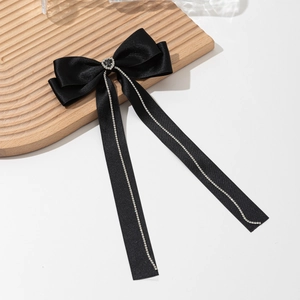 Close-up of black satin bow hair clip featuring a rhinestone heart and sparkling tassels