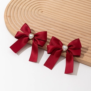 Close-up of red satin bow hair clips with heart pearl centers on wooden tray
