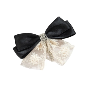 Detail of lace bow hair clip with sparkling rhinestone tassels and floral embroidery