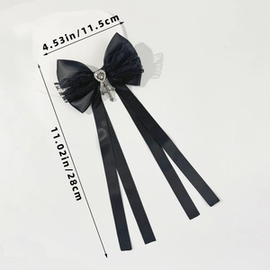 Détail du nœud en satin noir avec dentelle, strass en cœur et pendentif en croix