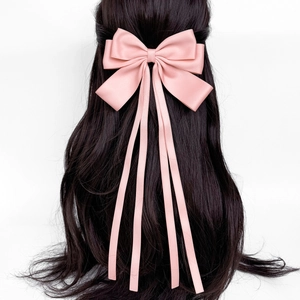 Detailed view of the elegant pale pink satin bow hair clip with long silk ribbons