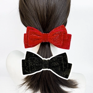 Detail view of red and black velvet bow hair clips with glitter for festive holiday styles