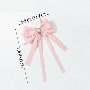 Détail de la barrette à cheveux en soie rose avec strass en cœur et longs rubans