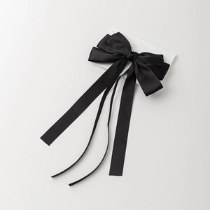 Detailansicht einer schwarzen Satin-Haarschleife mit eleganten langen Bändern auf Marmor