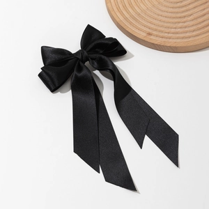 Detail of elegant black satin bow hair clip with long streamers and silky texture