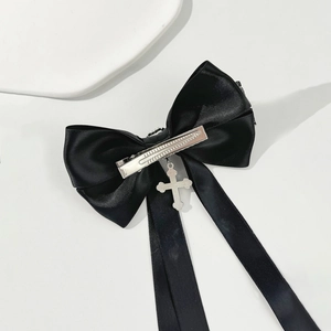 Détail d'une pince à cheveux à nœud noir avec croix argentée et centre en cristal
