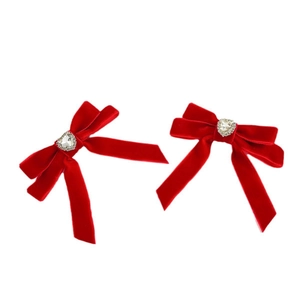 Detail of red velvet bow hair clips with heart-shaped crystal center on white background