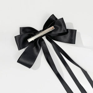 Detailed close-up of a black satin bow hair clip with long ribbons and metal alligator clip