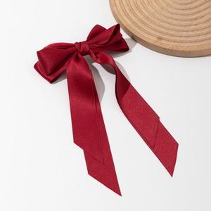 Elegant burgundy satin bow hair clip with long streamers on a white background