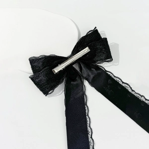 Detail of black lace ribbon hair clip with metallic duckbill clip on white tray