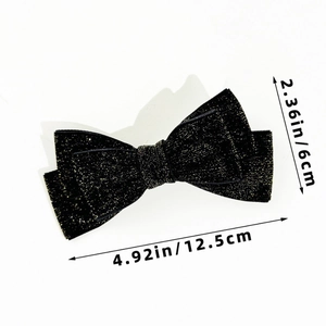Macro detail of the elegant black velvet bow clip showing metallic glitter fabric texture