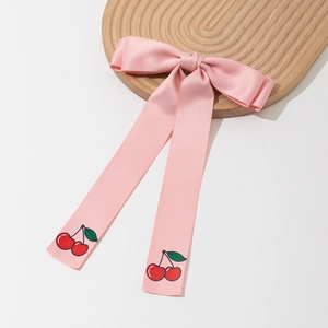 Sweet pink satin bow hair clip with cherry pattern ribbons on a wooden tray