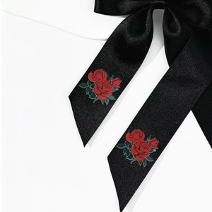 Detailed macro view of black satin bow with rose floral print on silky polyester fabric