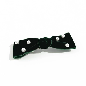 Detailed view of handmade dark green velvet bow hair clip with white pearl bead accents