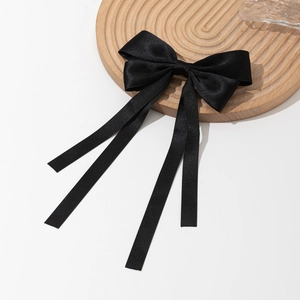 Détail d'un élégant nœud en satin noir avec de longs rubans fluides sur un plateau en bois