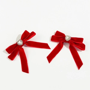 Detail of two red velvet bow hair clips with heart-shaped crystal center on white background