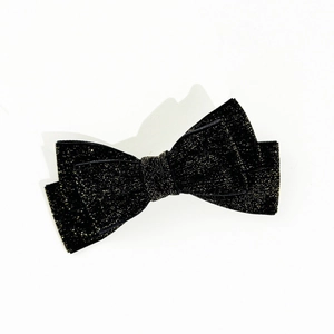 Detail of elegant black velvet Christmas bow hair clip with sparkling golden glitter texture