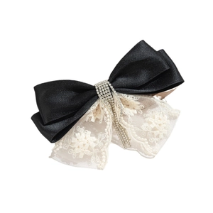Elegant black satin bow hair clip with white floral lace and shimmering rhinestone tassels