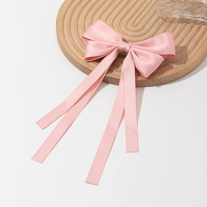 Barrette élégante en satin rose avec longs rubans sur un plateau en bois décoratif