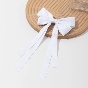 Pince à cheveux élégante en satin blanc avec ruban sur un plateau en bois texturé